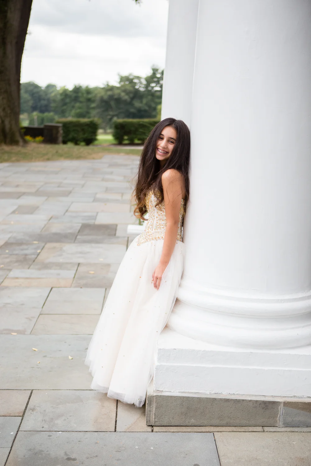 Photo of Bat Mitzvah girl in gown leaning against large column