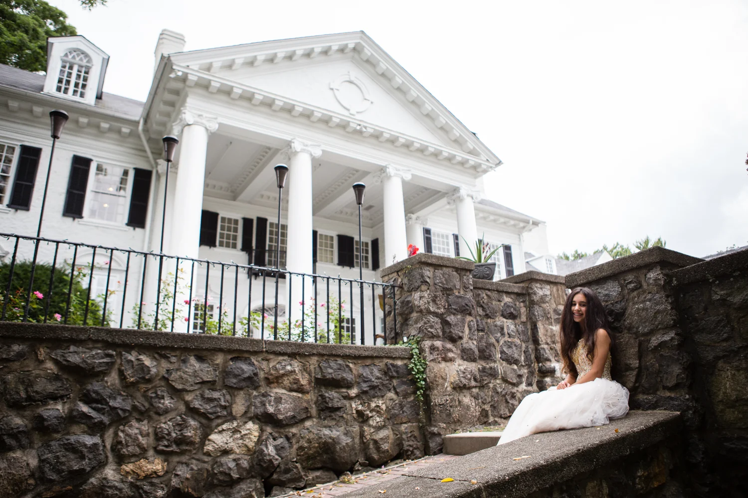 Photo of bat mitzvah girl in white gown in front of old white columned building