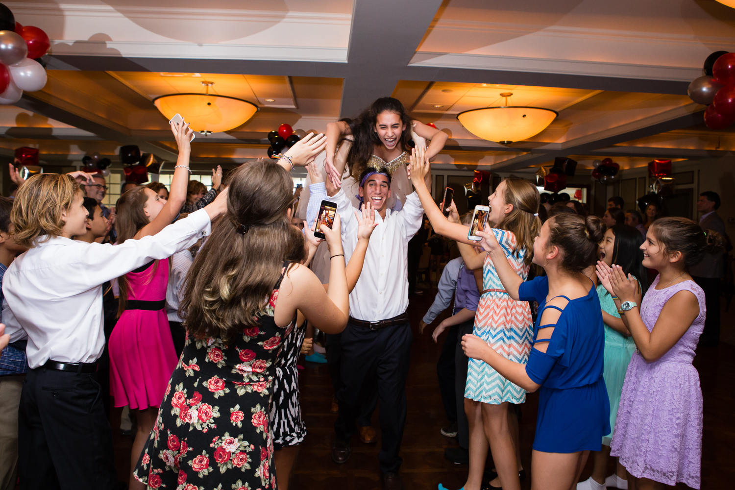 Photo of girl being carried into hall at Bat Mitzvah party