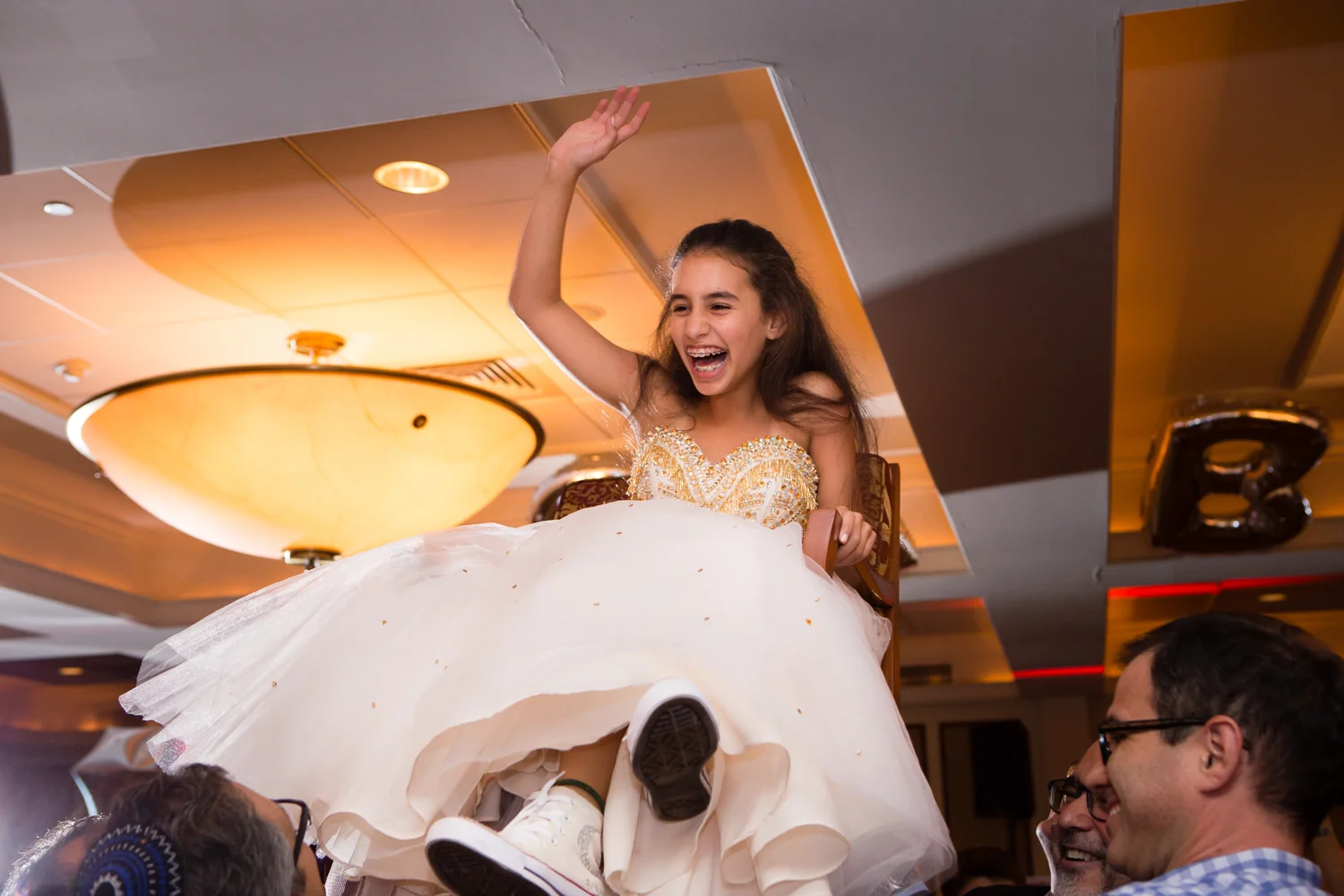 Photo of bat mitzvah girl laughing on chair during hora dance