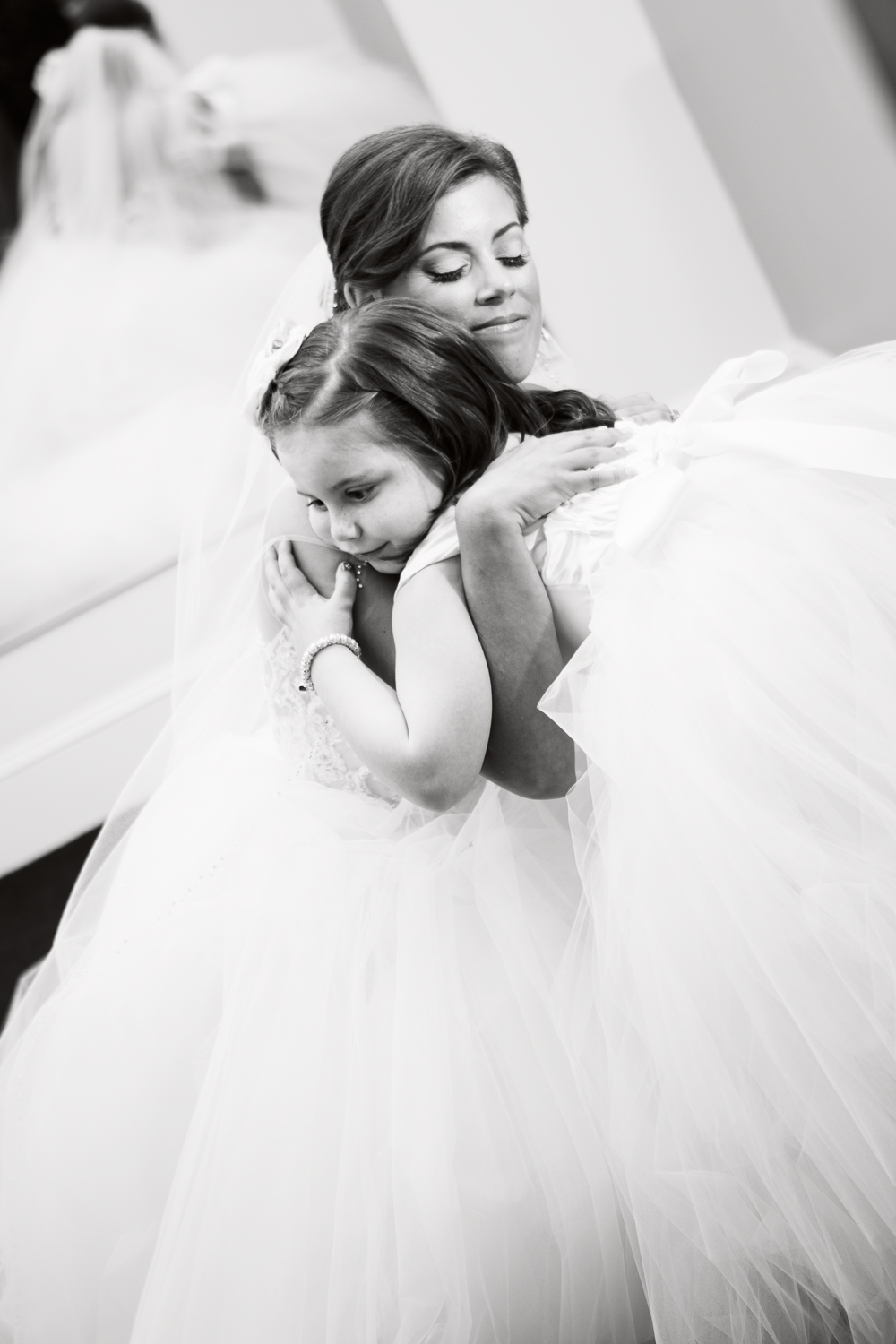 Black and white photo of bride hugging the flower girl
