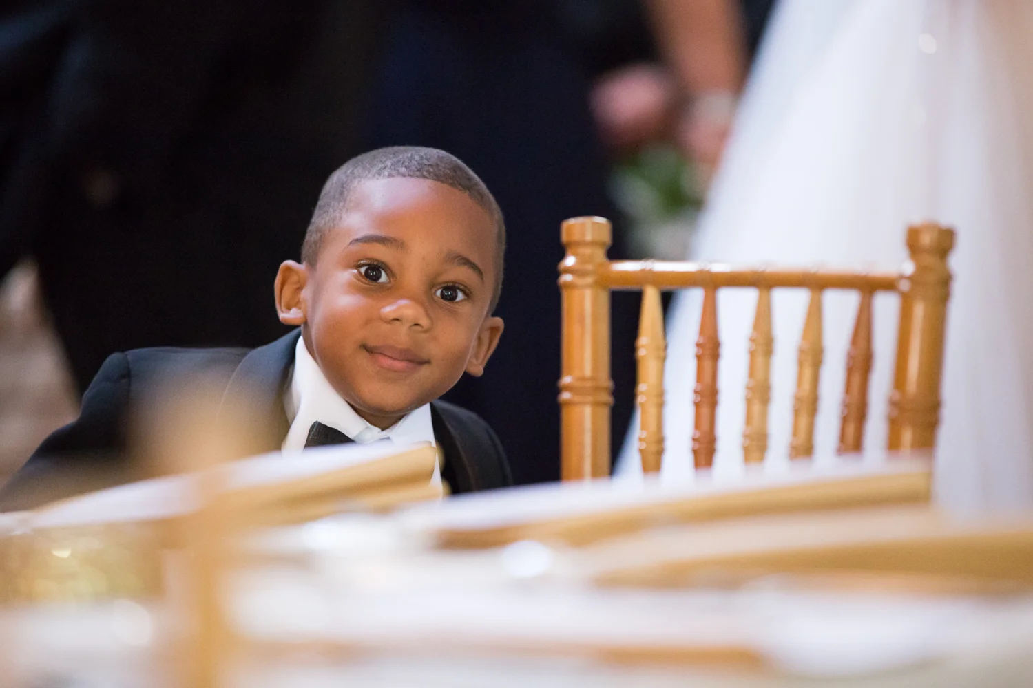 Photo of little boy in a tux at wedding reception
