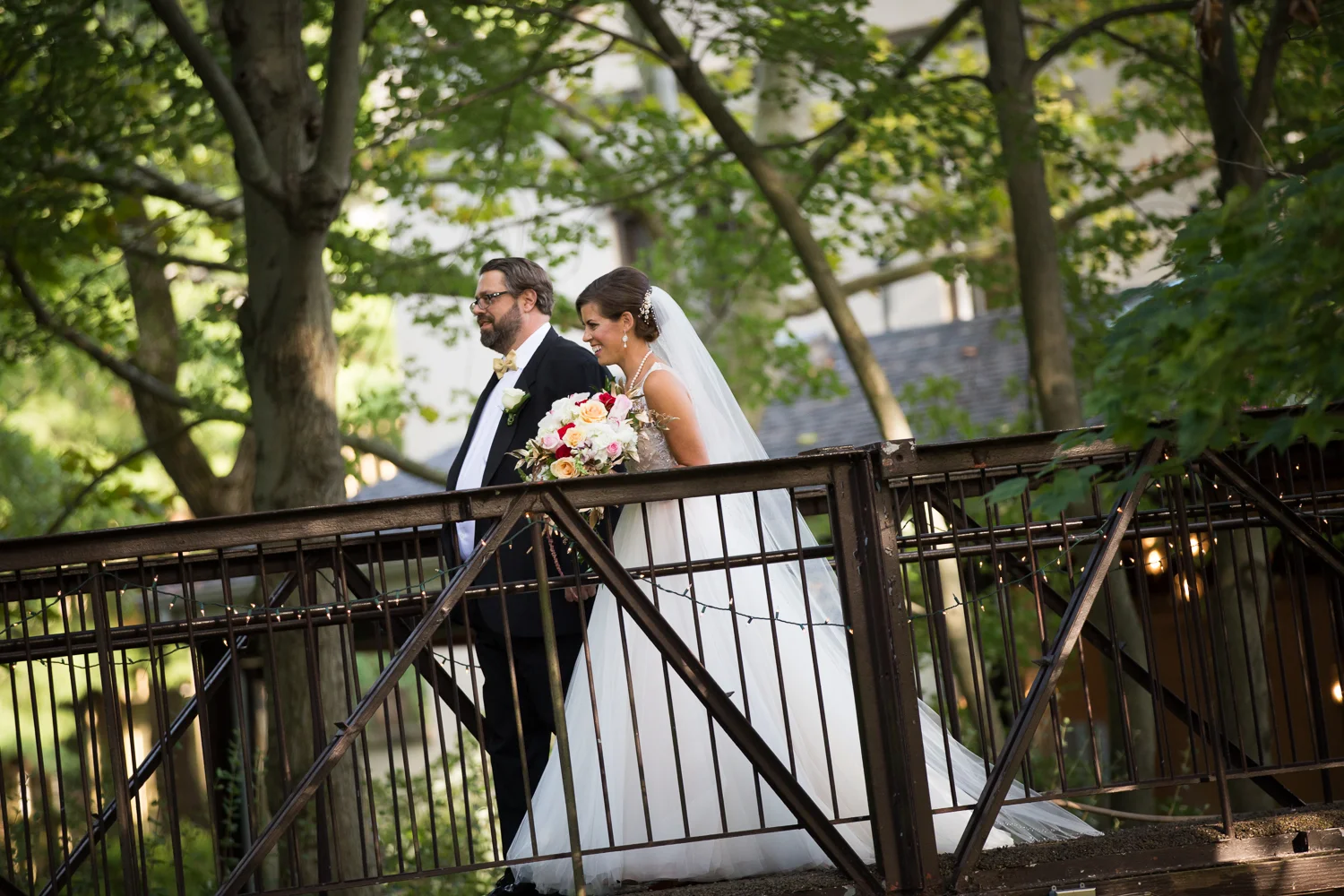 Photo of bride being walked down aisle on the bridge at The Pomme in Radnor