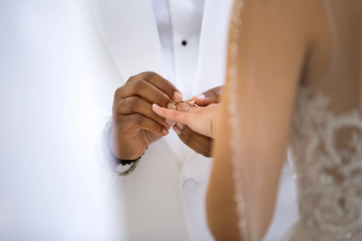 Photograph of groom's hands placing ring on bride's finger