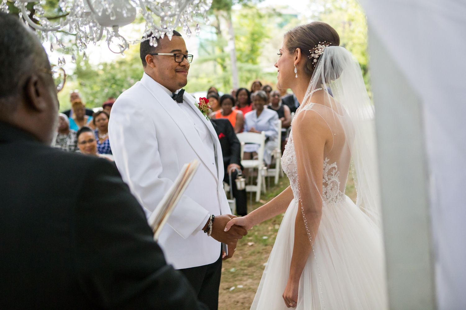 Photo of black groom and white bride during outdoor ceremony