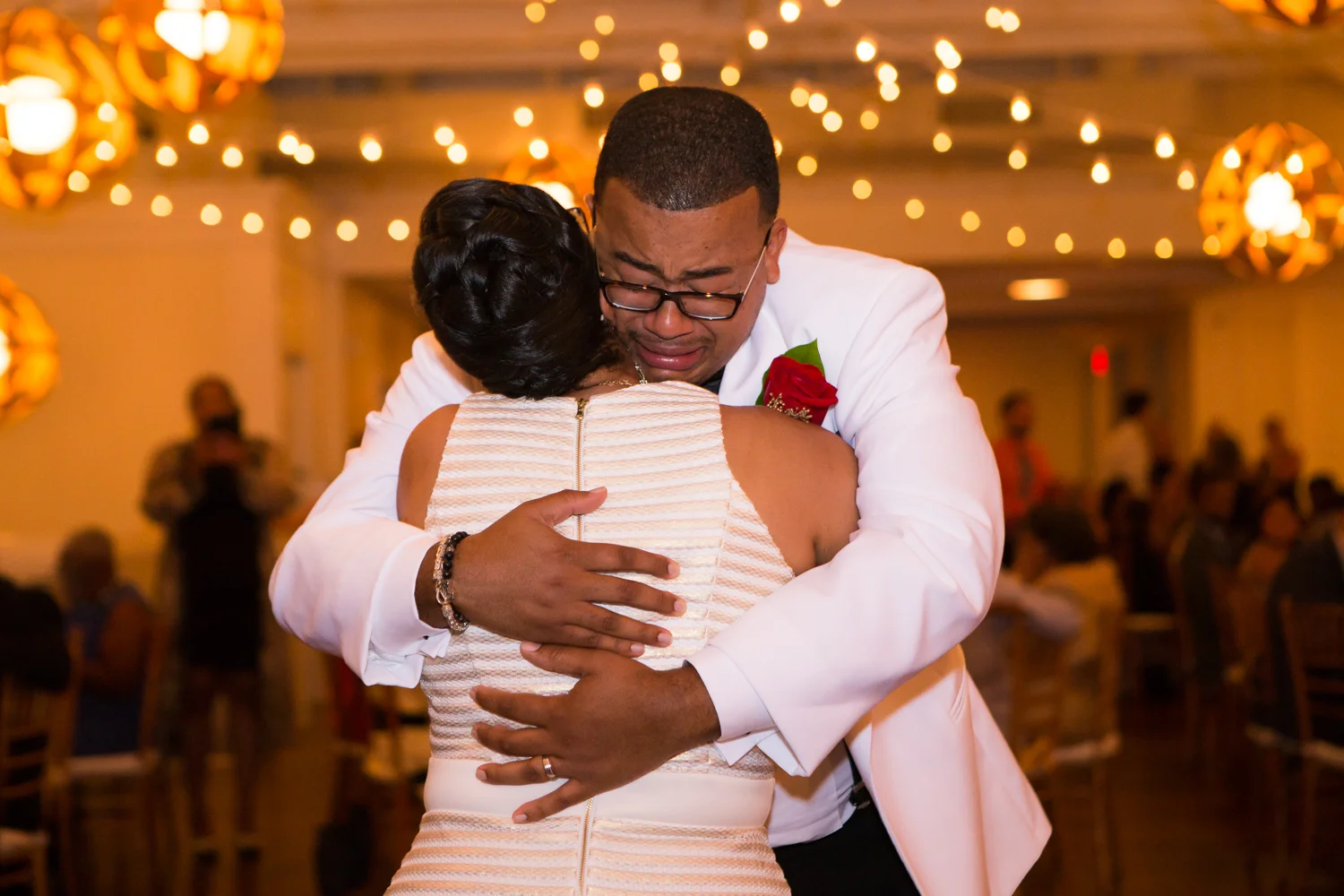 Photo of groom crying during mother son dance at wedding reception