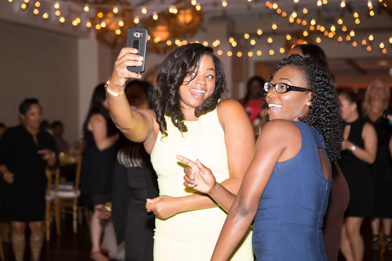 Photo of two black women taking a selfie at wedding reception