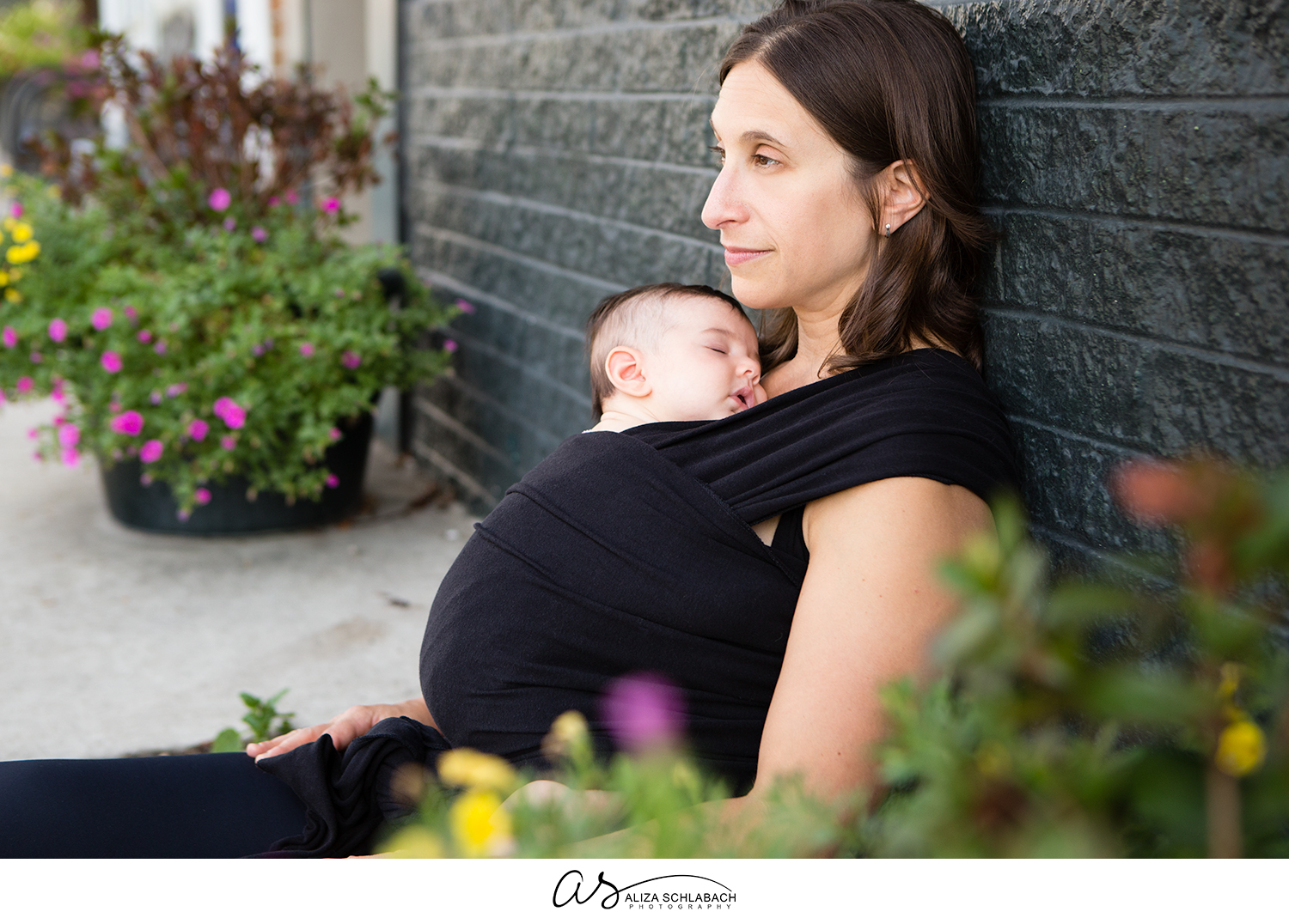 Outdoor photograph of a sleeping baby being worn by mom