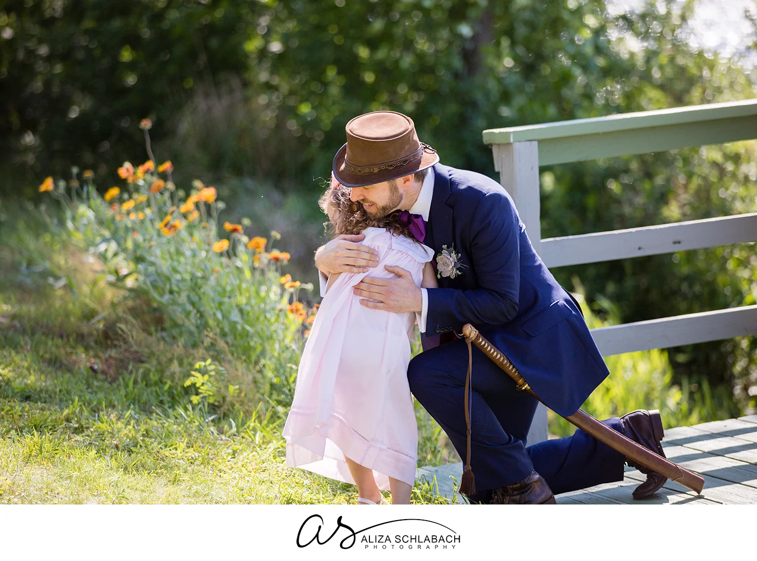Photo of groom hugging a flower girl during his wedding ceremony