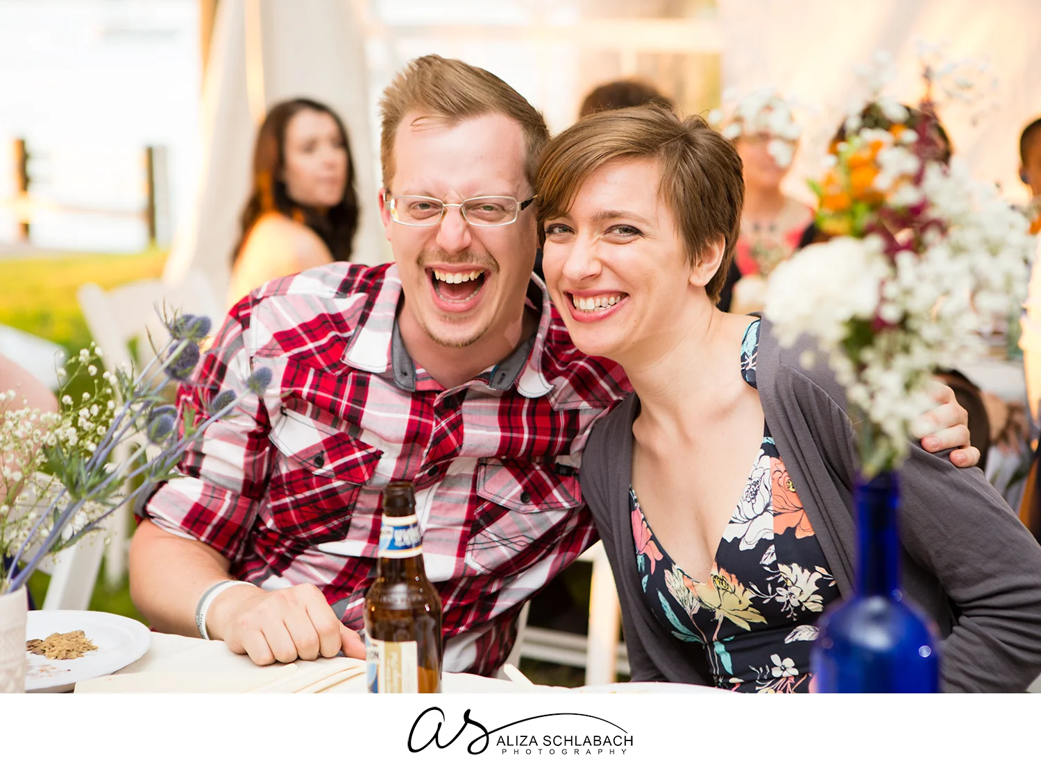 Photo of 2 laughing guests at a wedding reception in a tent