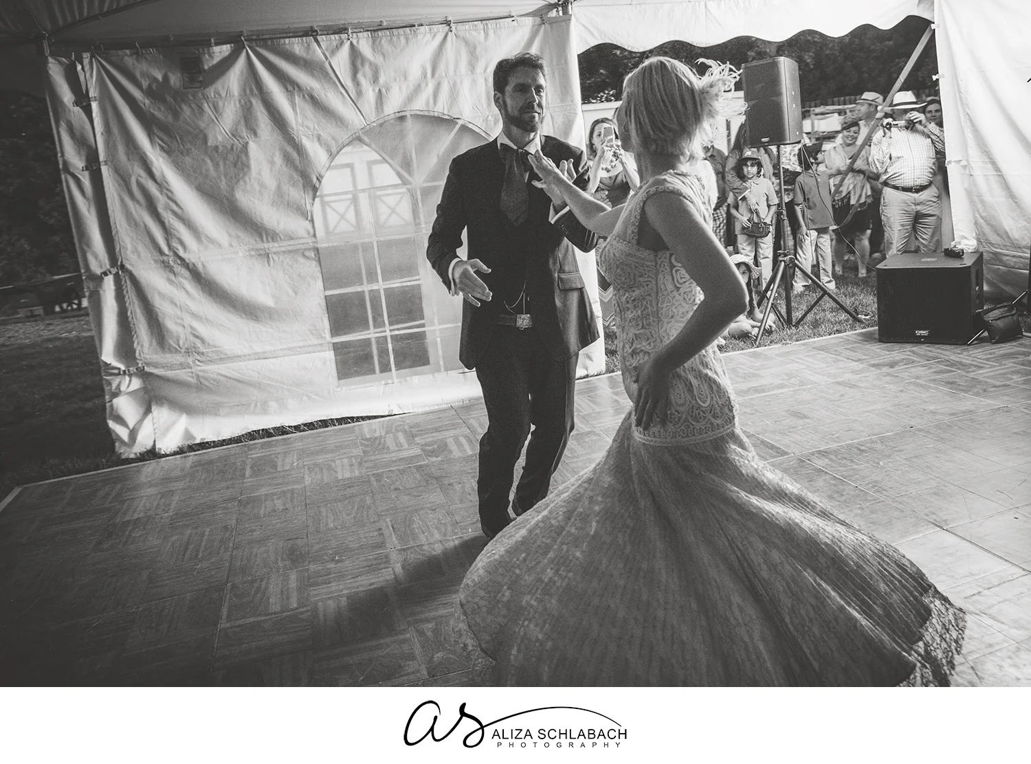 Black and white photograph of groom twirling his bride during first dance at their wedding