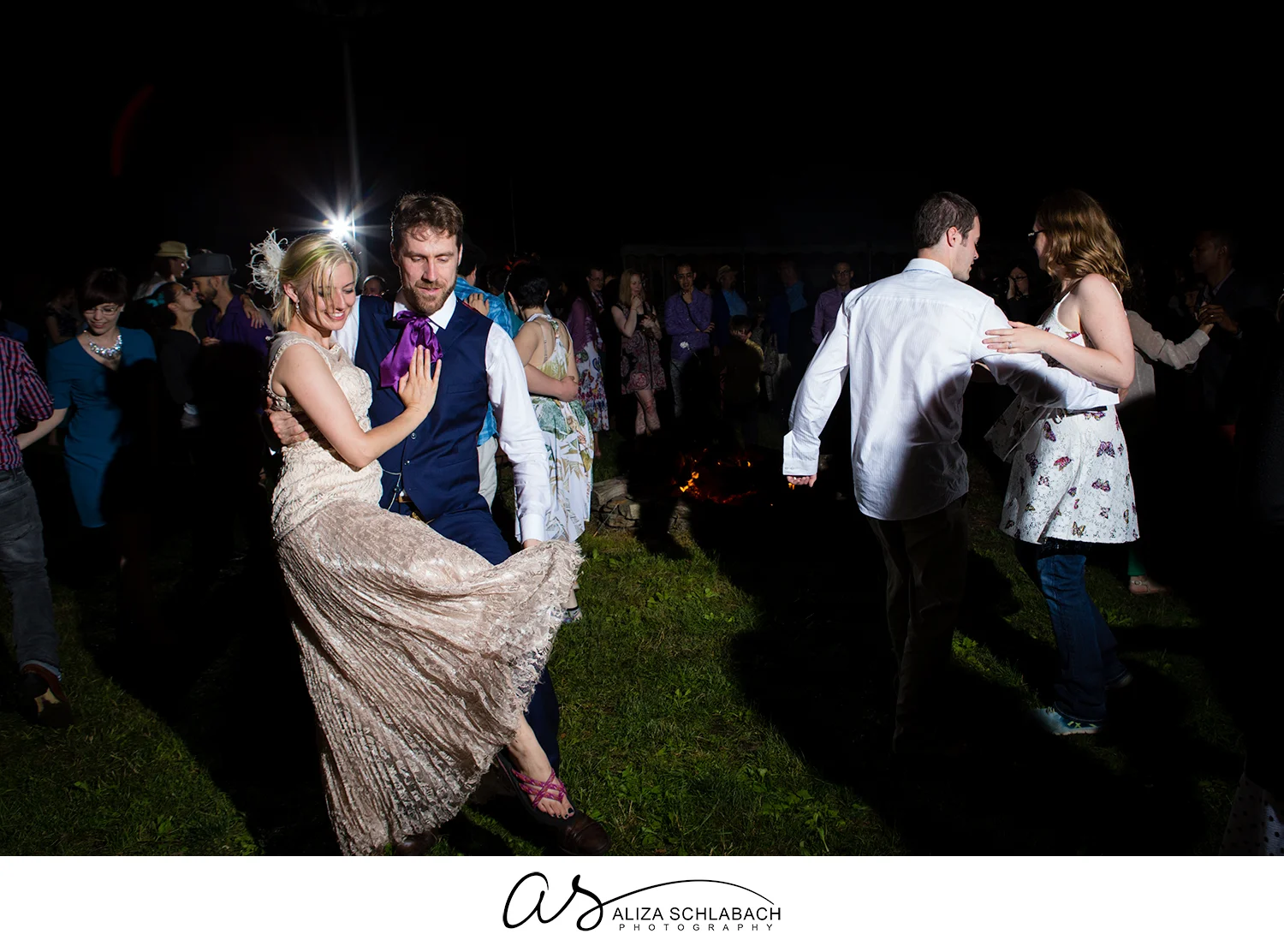 Photograph of bride and groom dancing outside at night during reception