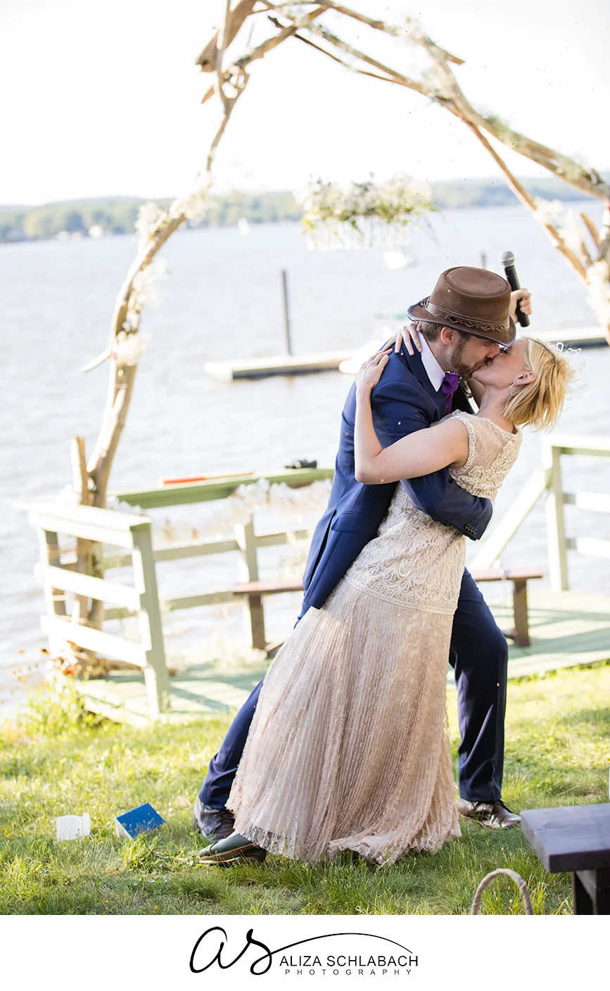 Photo of groom kissing and dipping his bride by the water