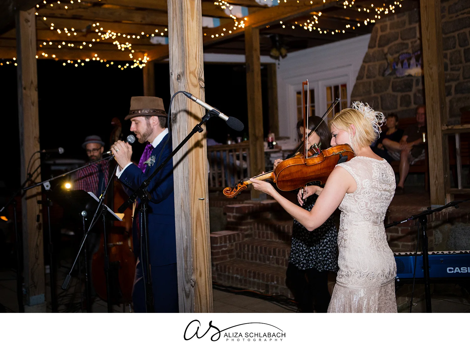 Photo of groom singing and bride playing viola during outdoor wedding reception