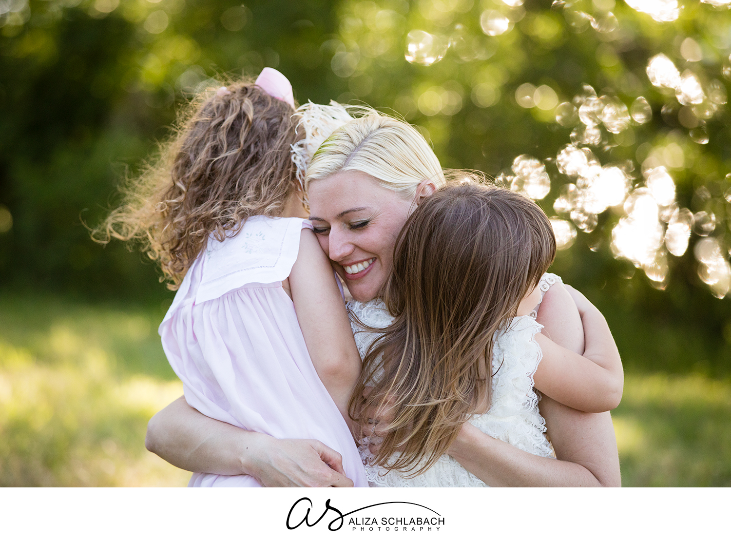 Photograph of bride hugging her flower girls outside