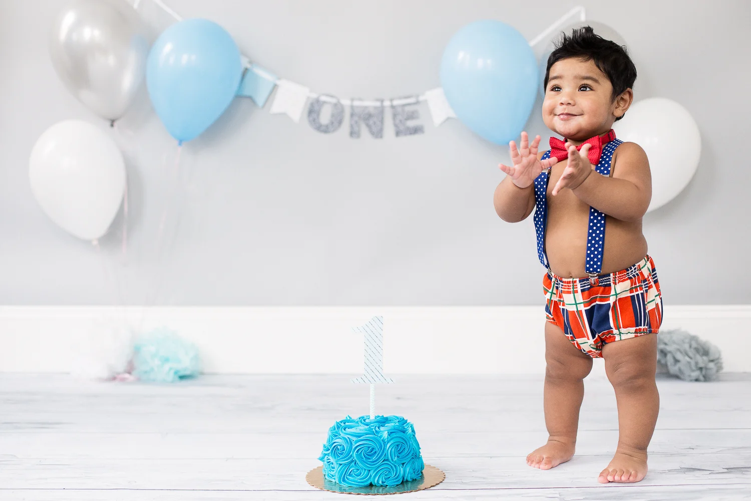 1 year old boy clapping at his cake smash photo shoot