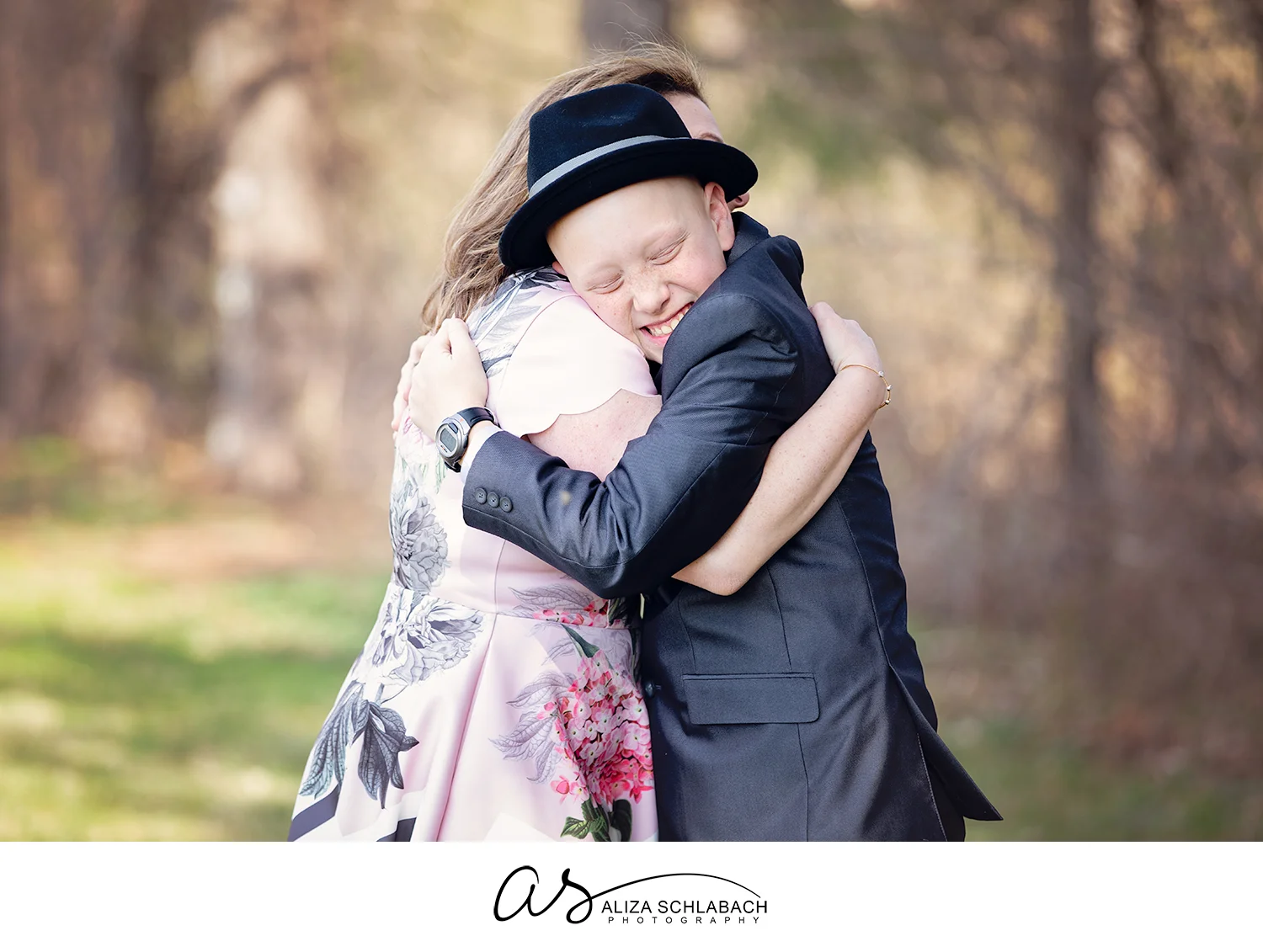 Outdoor photo of a boy in a suit hugging his mom