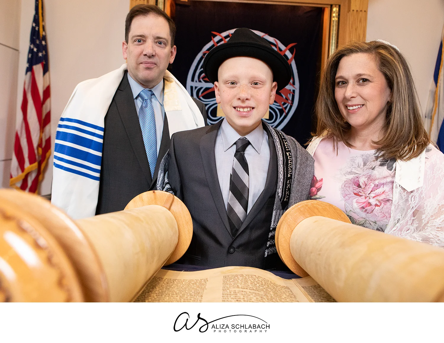 Portrait of Bar Mitzvah boy with his parents at the Torah