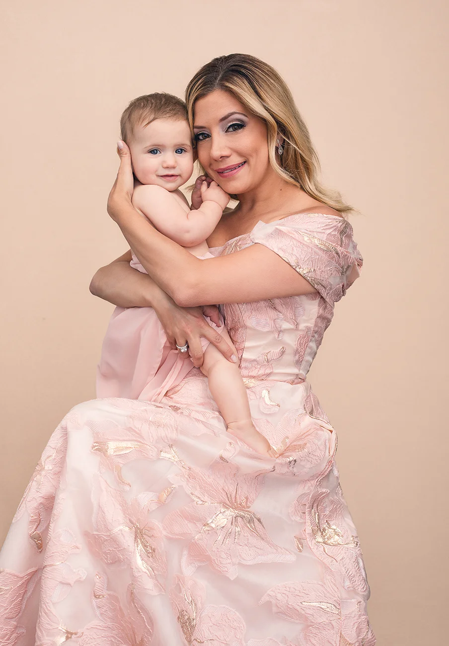 Portrait of a mother in a pink gown holding her baby daughter