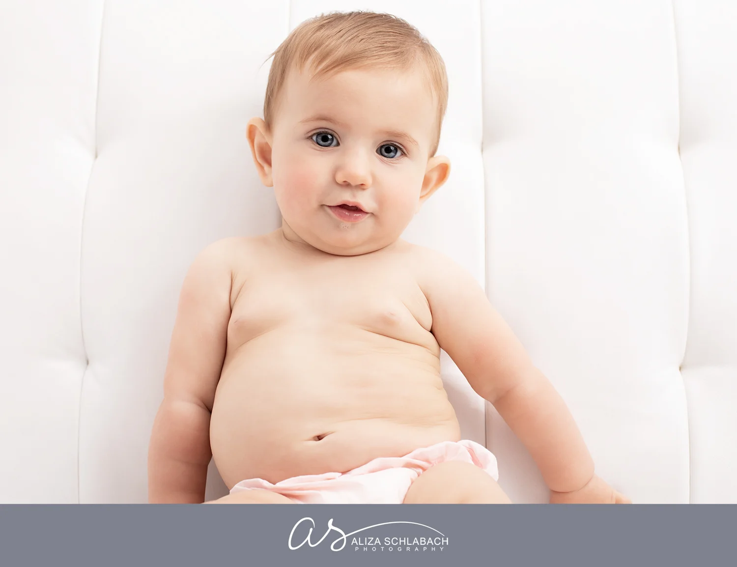 Photograph of a cute half naked baby girl on a white couch