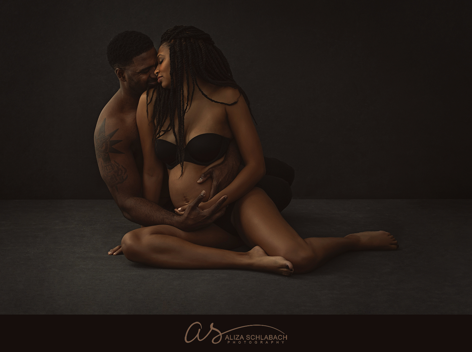 Seated maternity portrait of stunning black couple