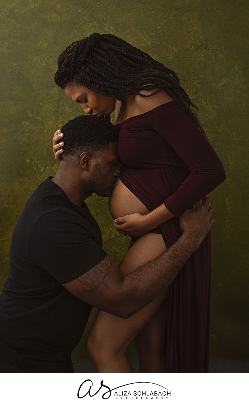 Portrait of husband kissing his pregnant wife's belly