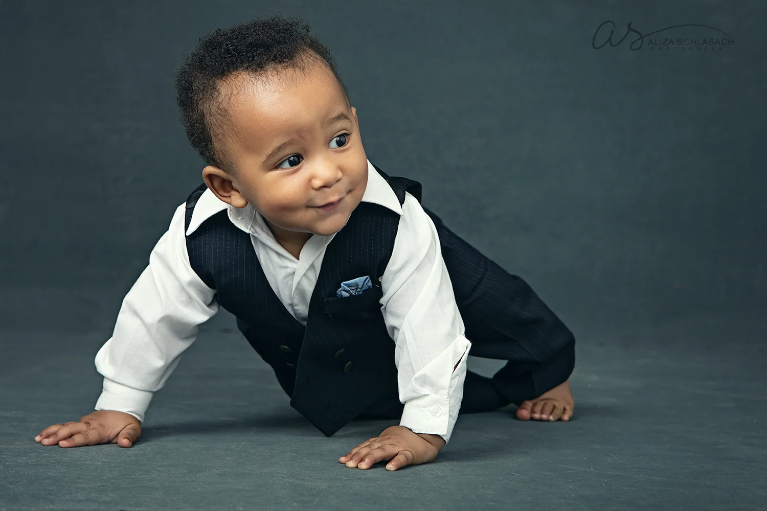 Photo of a cute crawling black baby wearing a suit