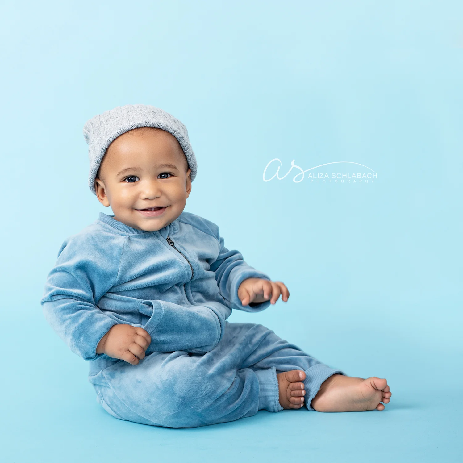 Photo of a cute smiling black baby in a hat and tracksuit on a blue background