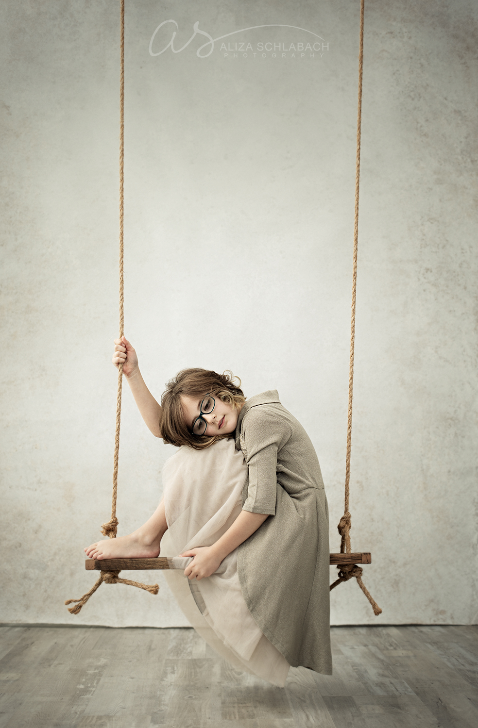 Fine art photo of a girl sitting sideways on a swing