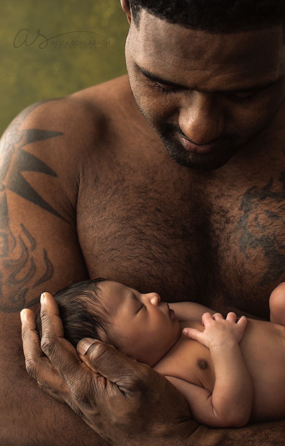 Portrait of a muscular black father holding his newborn daughter