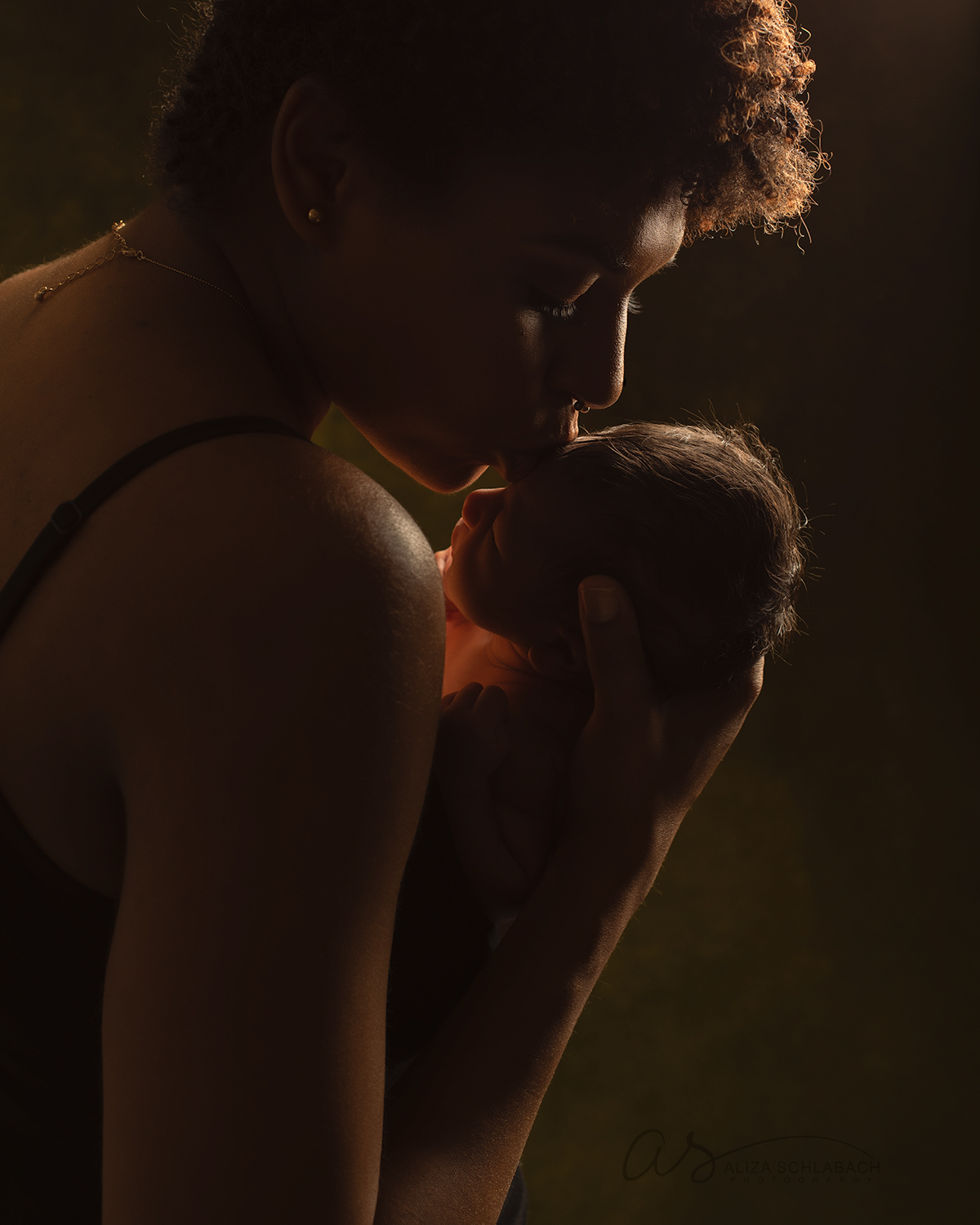 Silhouette of mother kissing her newborn daughter