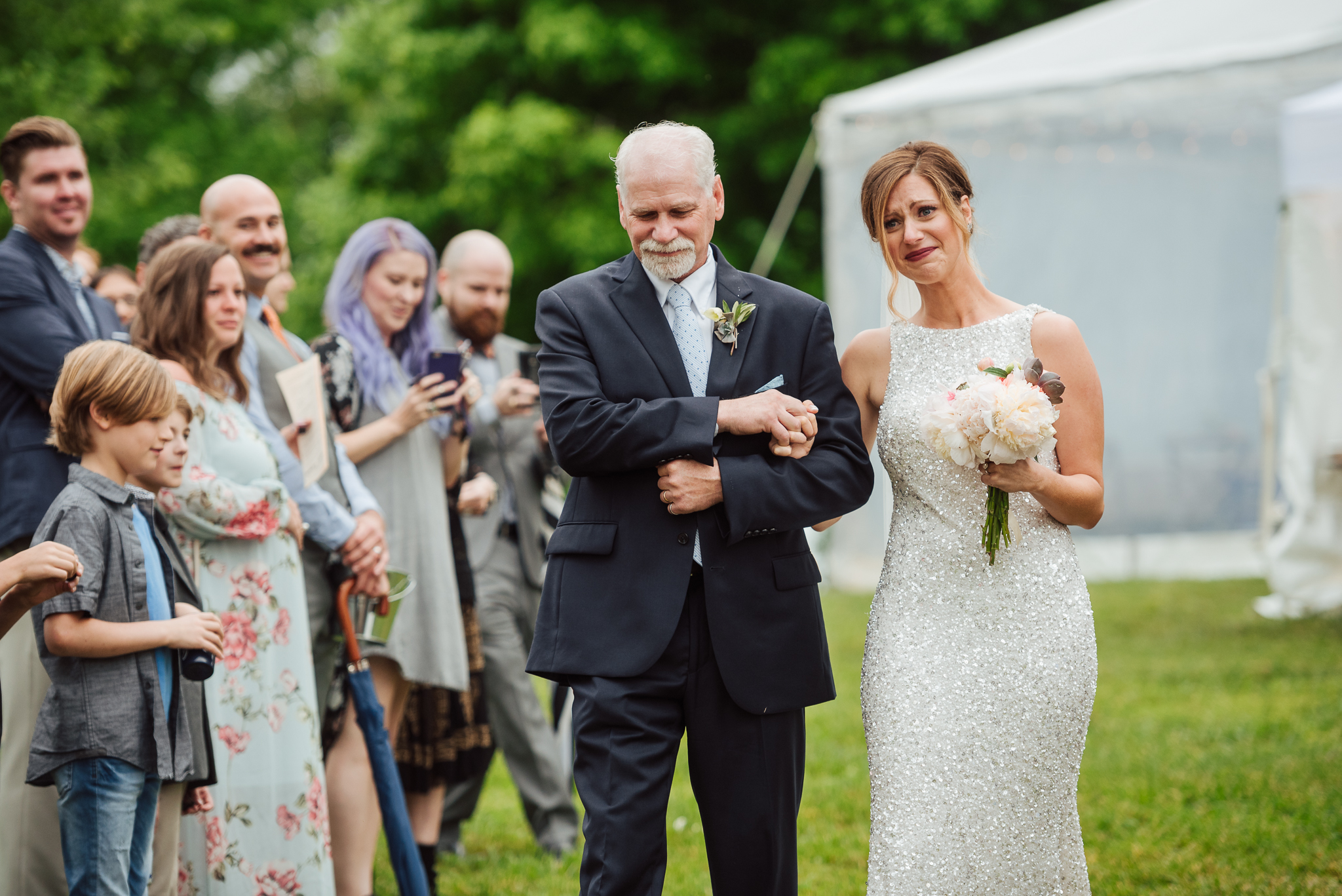 Emotional bride walking down aisle with father