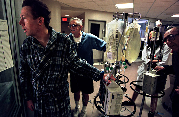 Arty, a stock-broker, peers through the windows of the intensive care unit at Joe who is resting just a few hours after the operation.