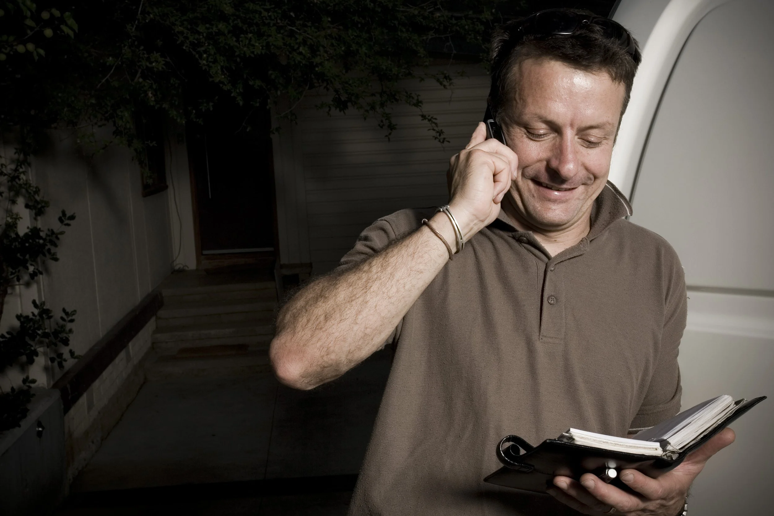 Qualified Canberra electrician talking on a cell phone to client as he makes appointment in his diary.