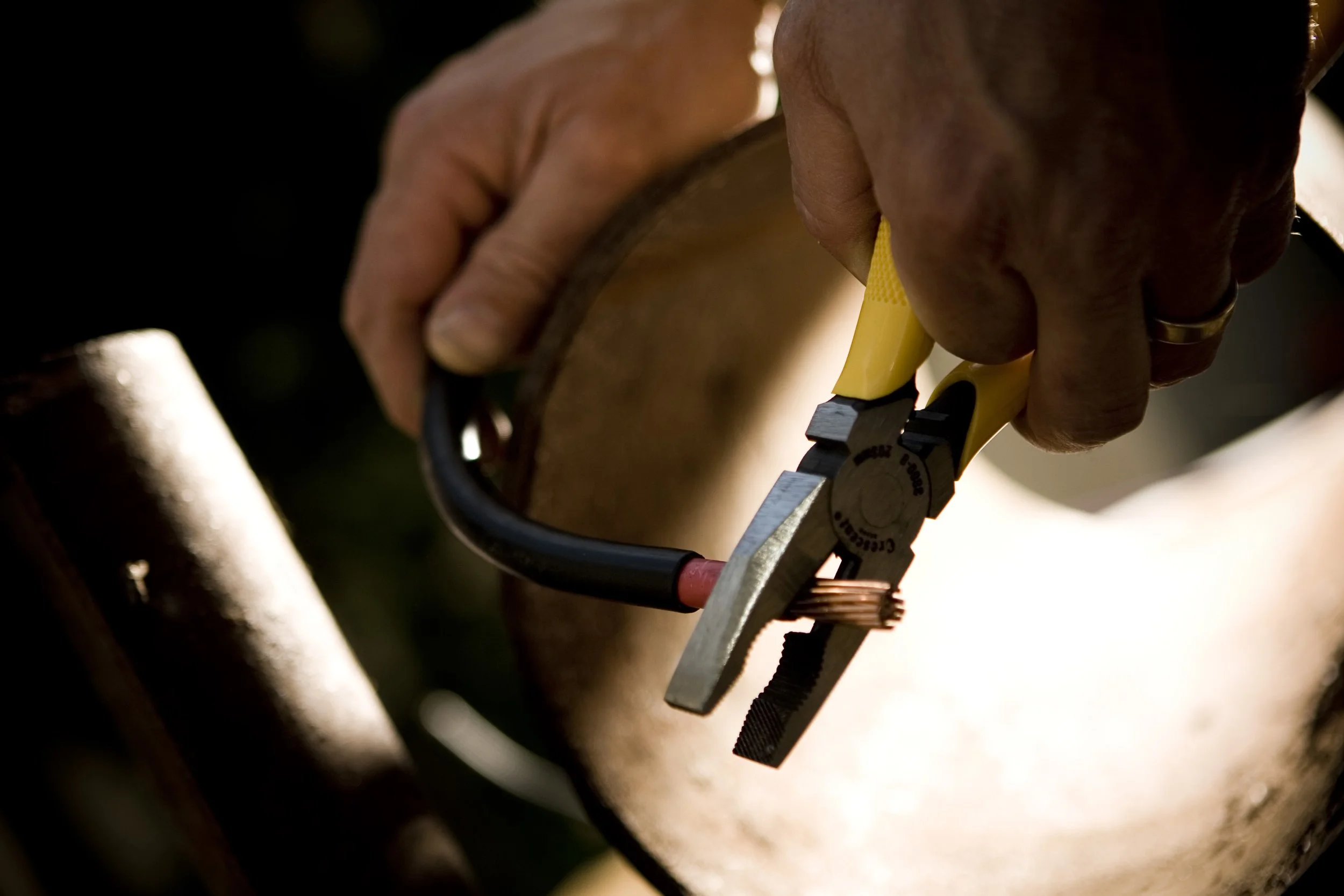 Close-up of a qualified Canberra electrician's hand using a pipe wrench to adjust power for outdoor lighting installation.