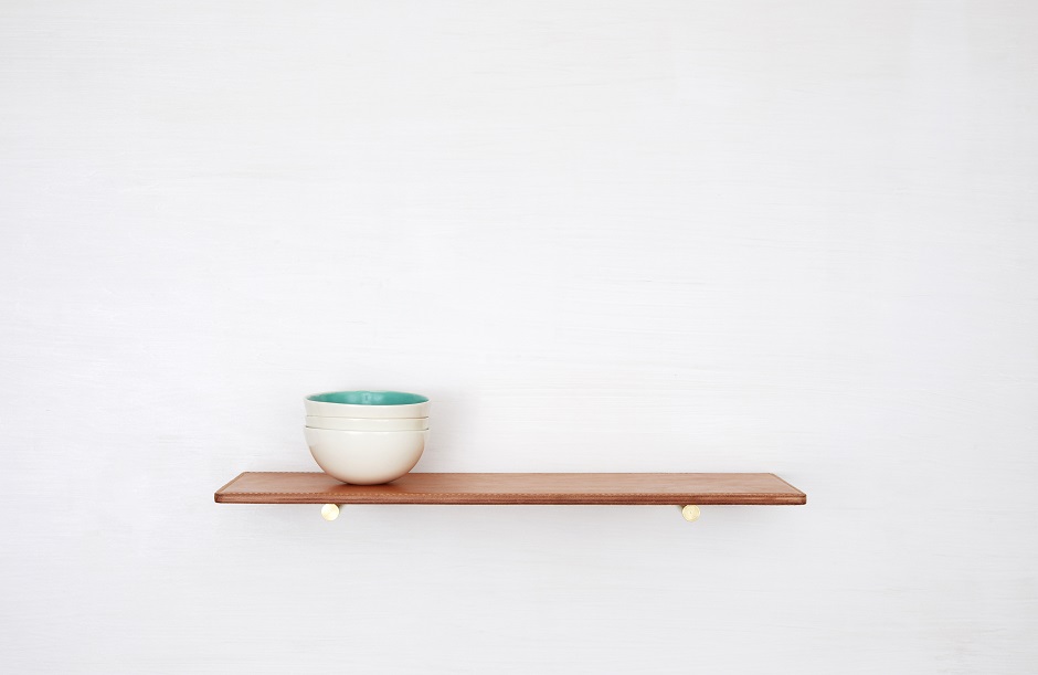 Natural leather shelf with decorative stack of bowls