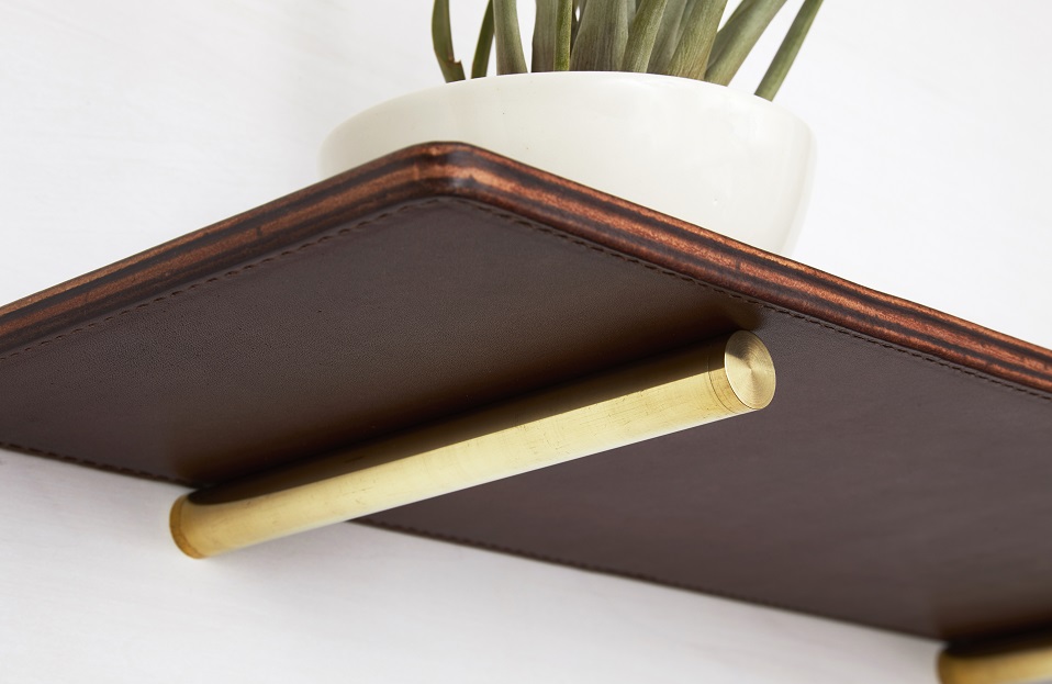 Underside of brown leather shelf and solid brass supports