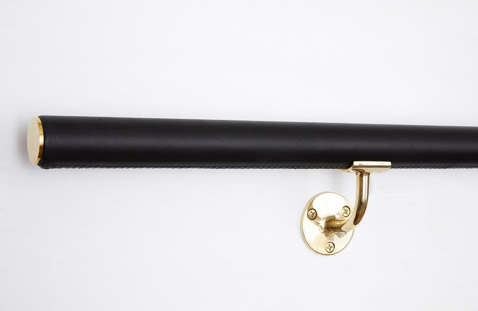 Close up of hand stitching and modern brass supports on black handrail