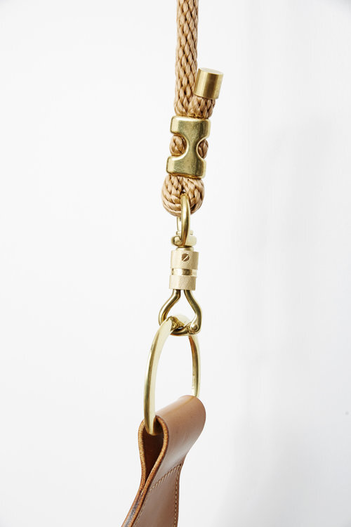 Close up of brass hardware and braided polyester rope on brown leather swing