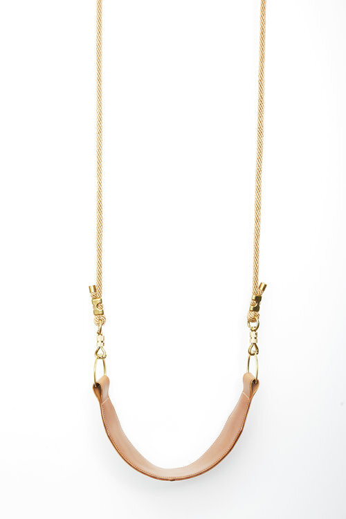 Close up of brown leather swing against a white background 