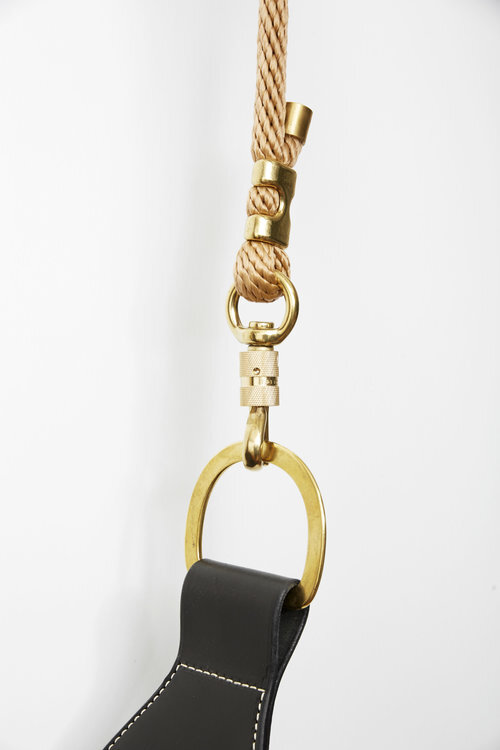 Close up of brass hardware and braided polyester rope on black leather swing