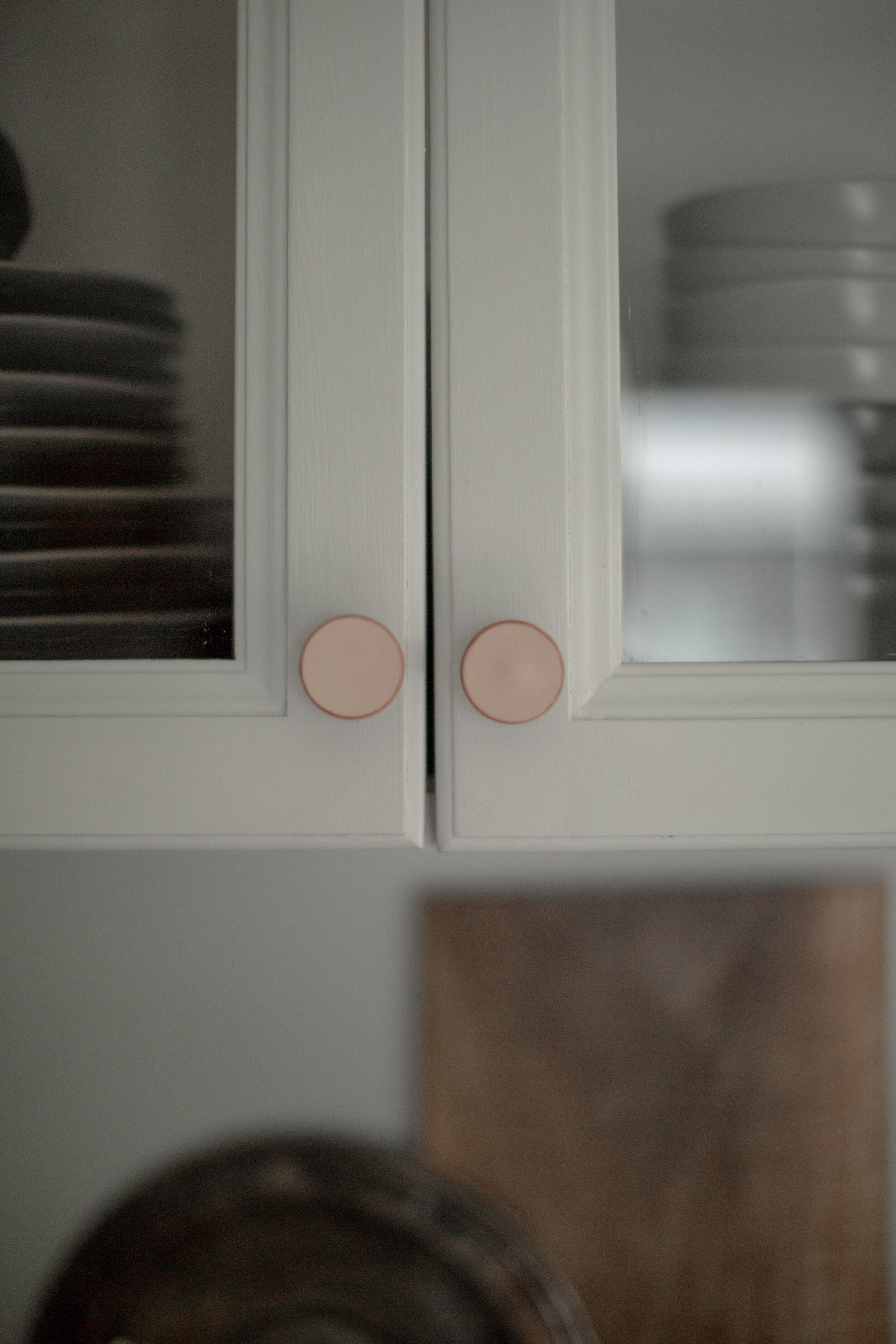 Pair of natural skirting leather knobs shown on white cabinet doors