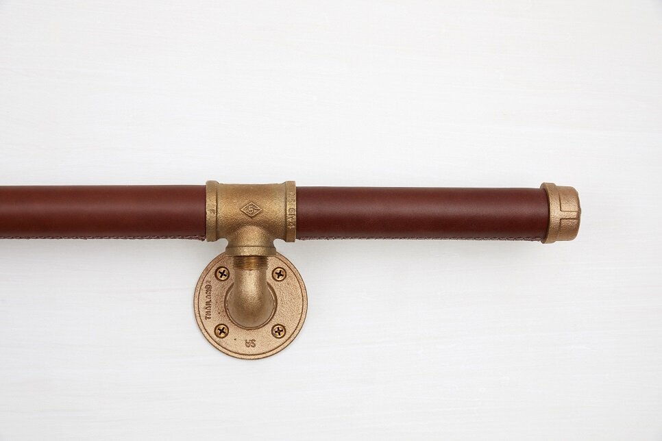 Close up of industrial brass supports on brown leather handrail