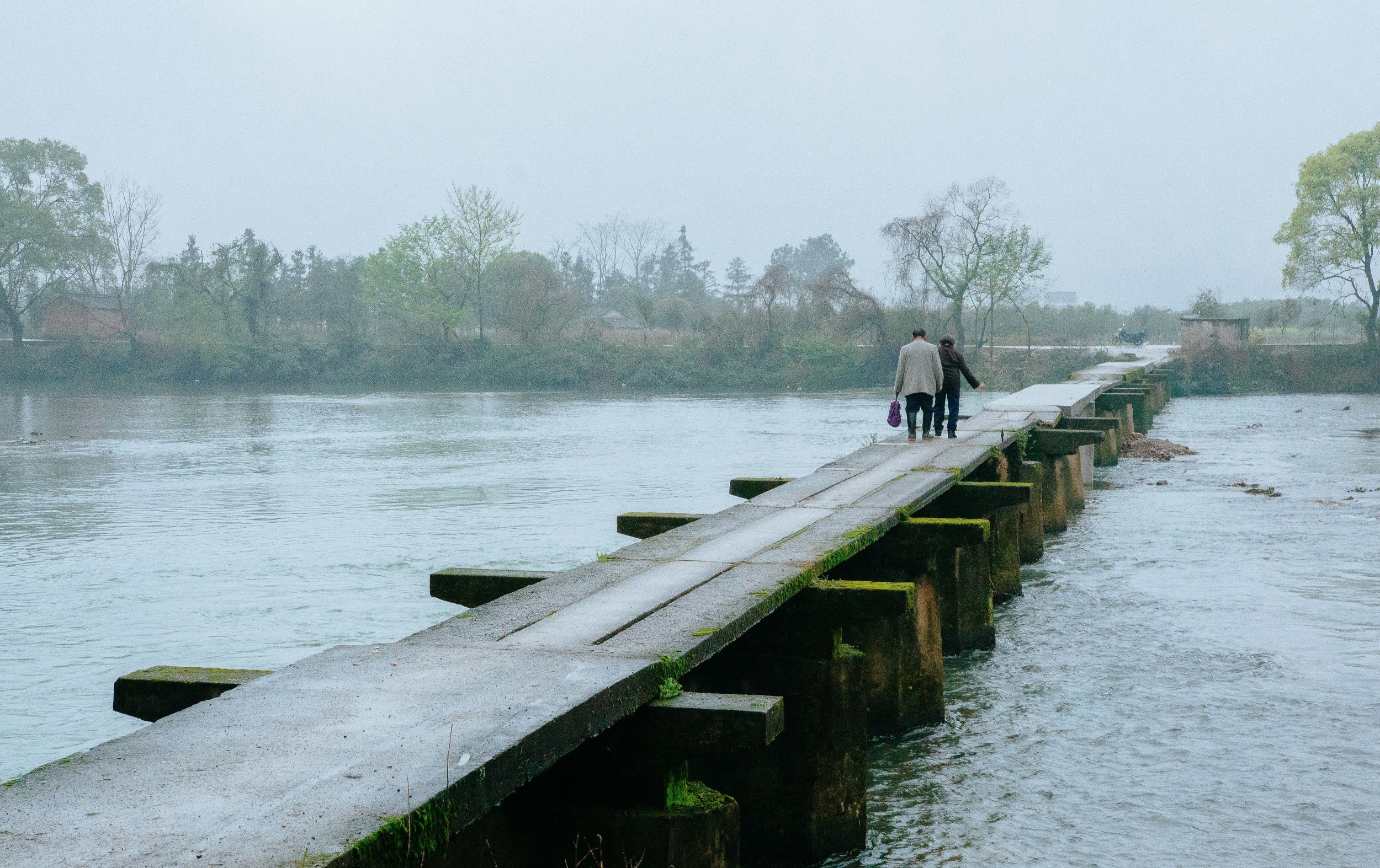 The Crossing - Skies clouded white, bridge worn down, waters turbulent– these elders have no fear in crossing. 