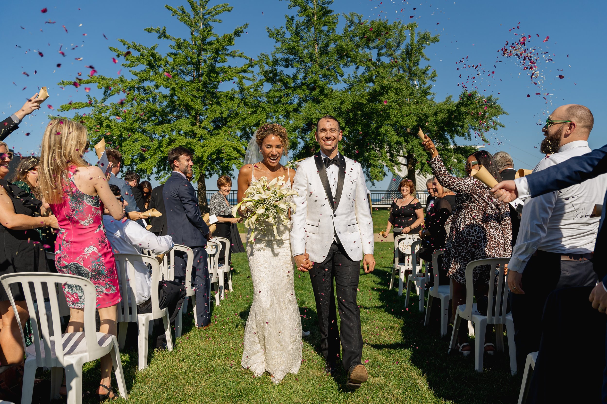 Couple walks down the aisle together while guests throw flower petals