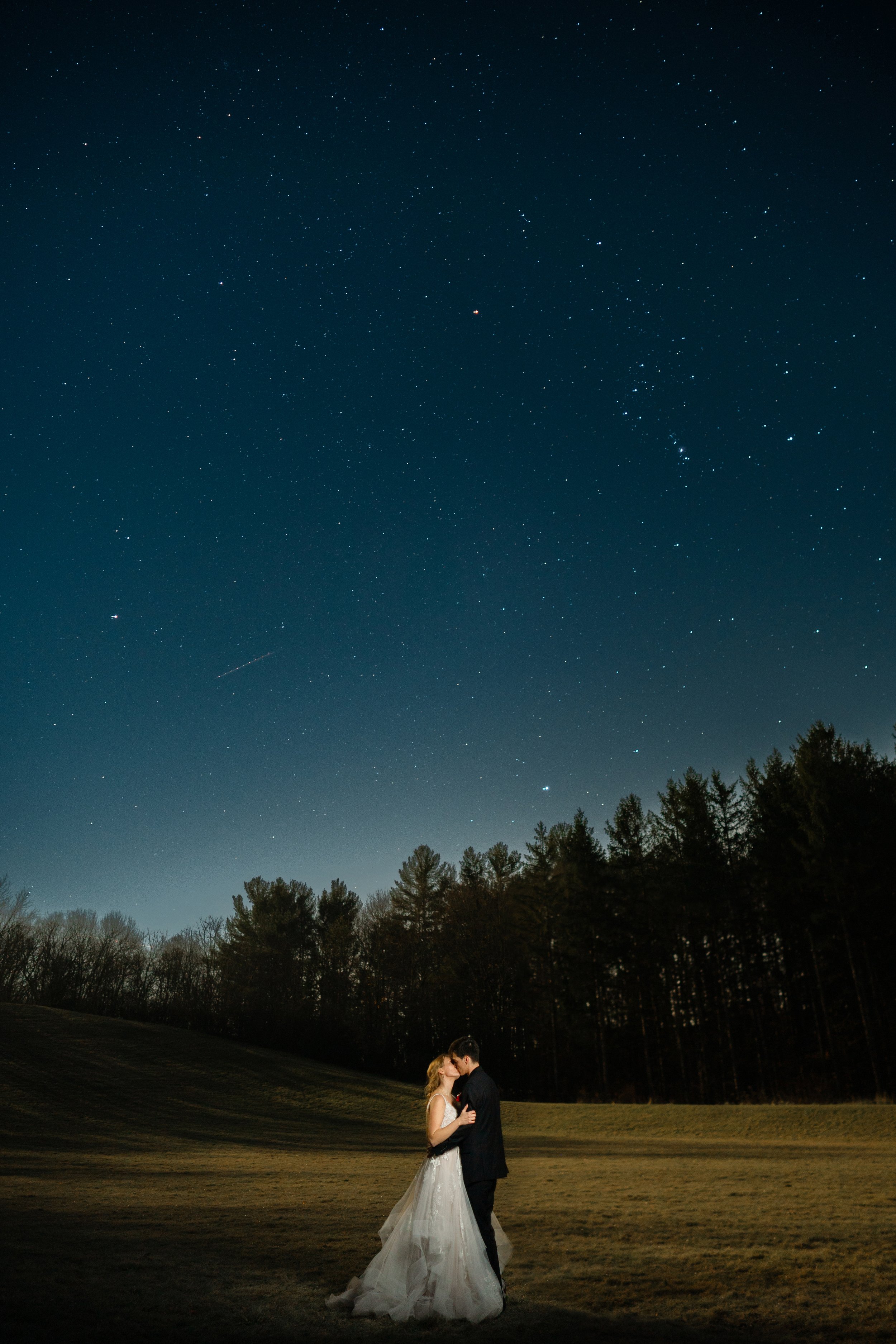 couple poses for a photo under the stars on the wedding day at Glacier Hills Hall and Chapel