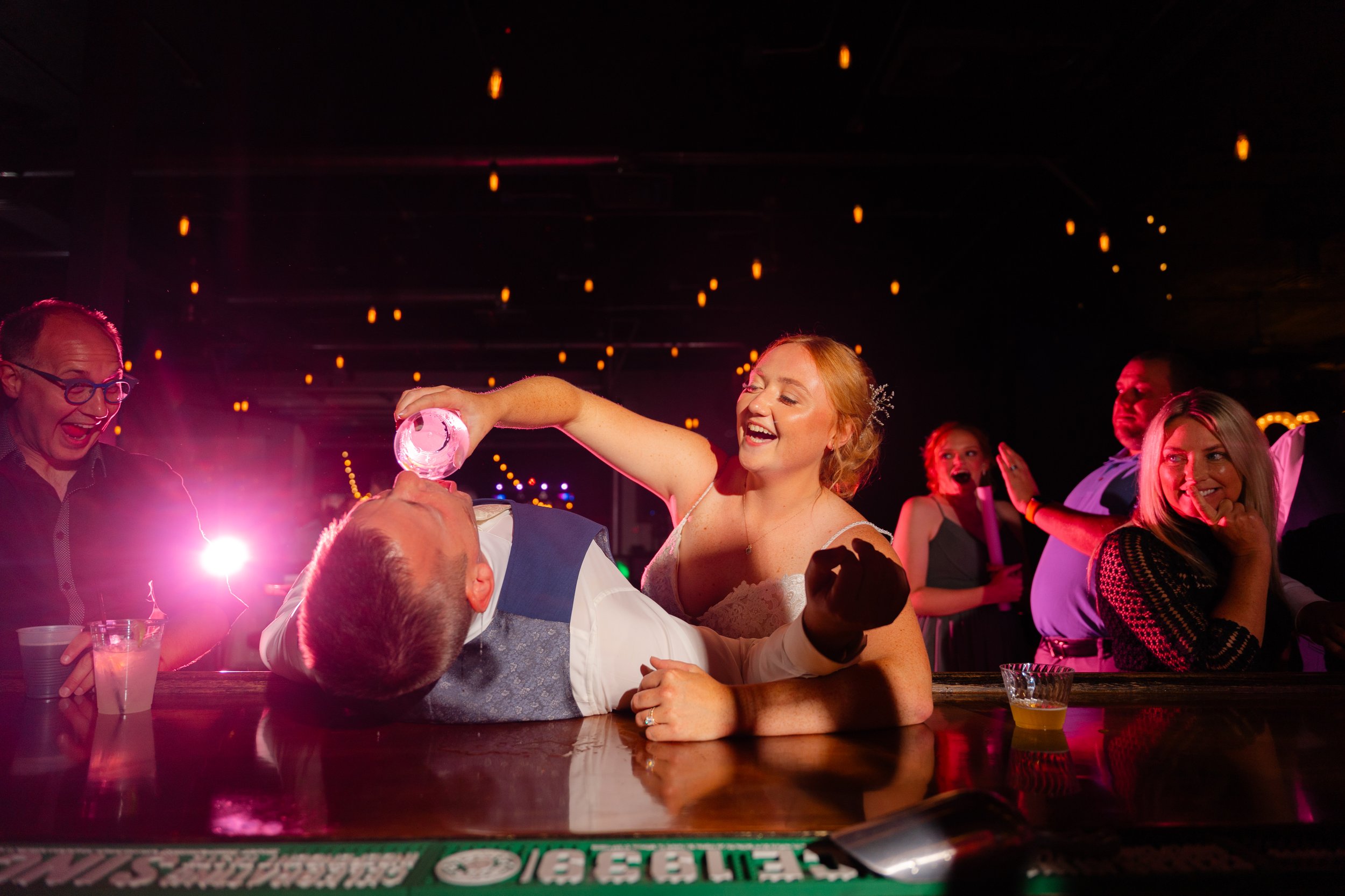 Bride pours a shot into the grooms mouth during the reception at Terrace 167