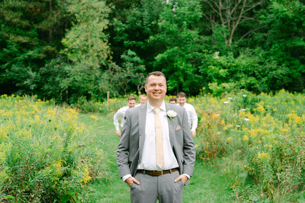A wedding day GIF of a groom getting tackled by his groomsmen