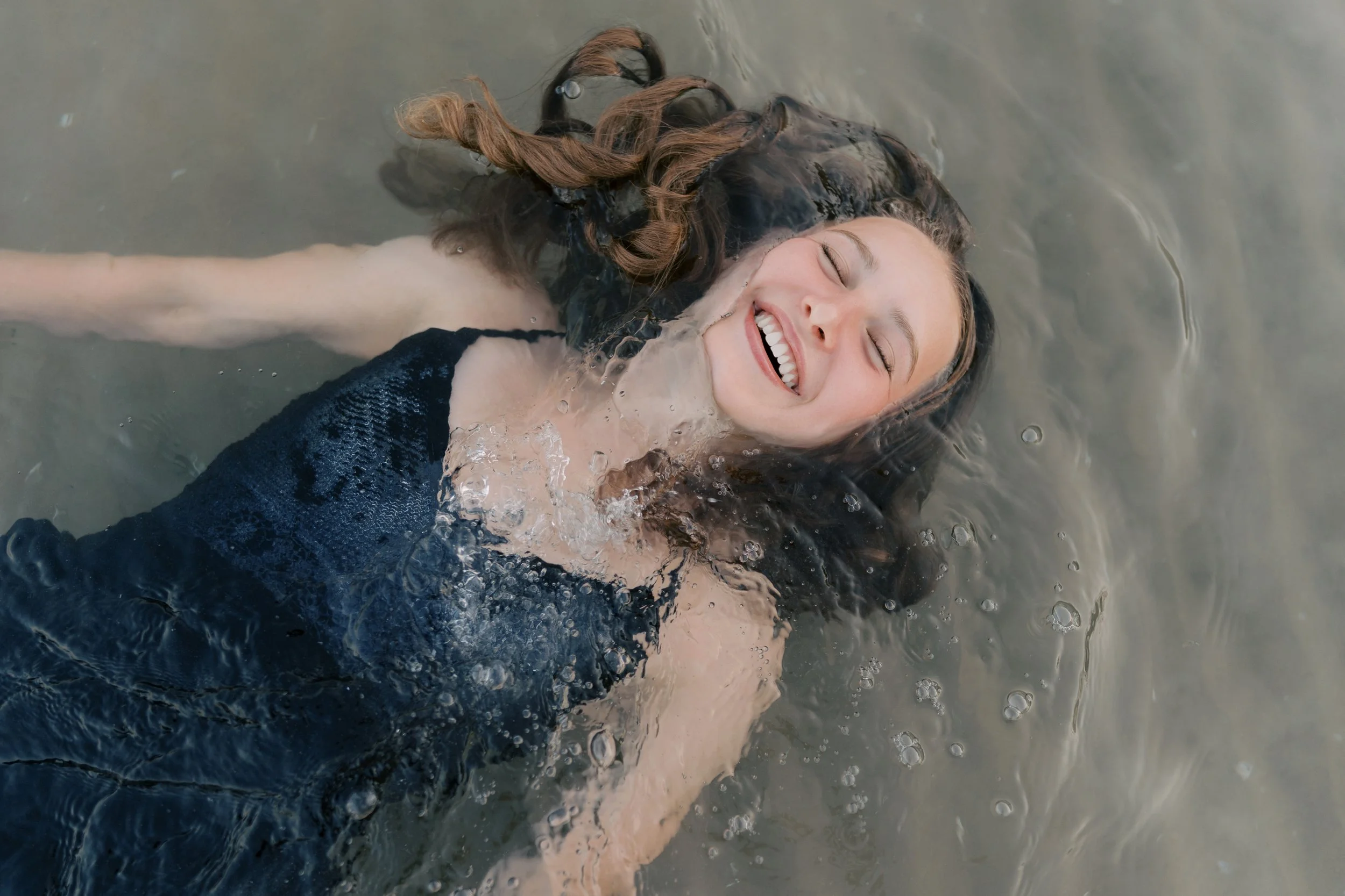Candid senior portrait session with a girl laughing in a lake in Port Washington, Wisconsin