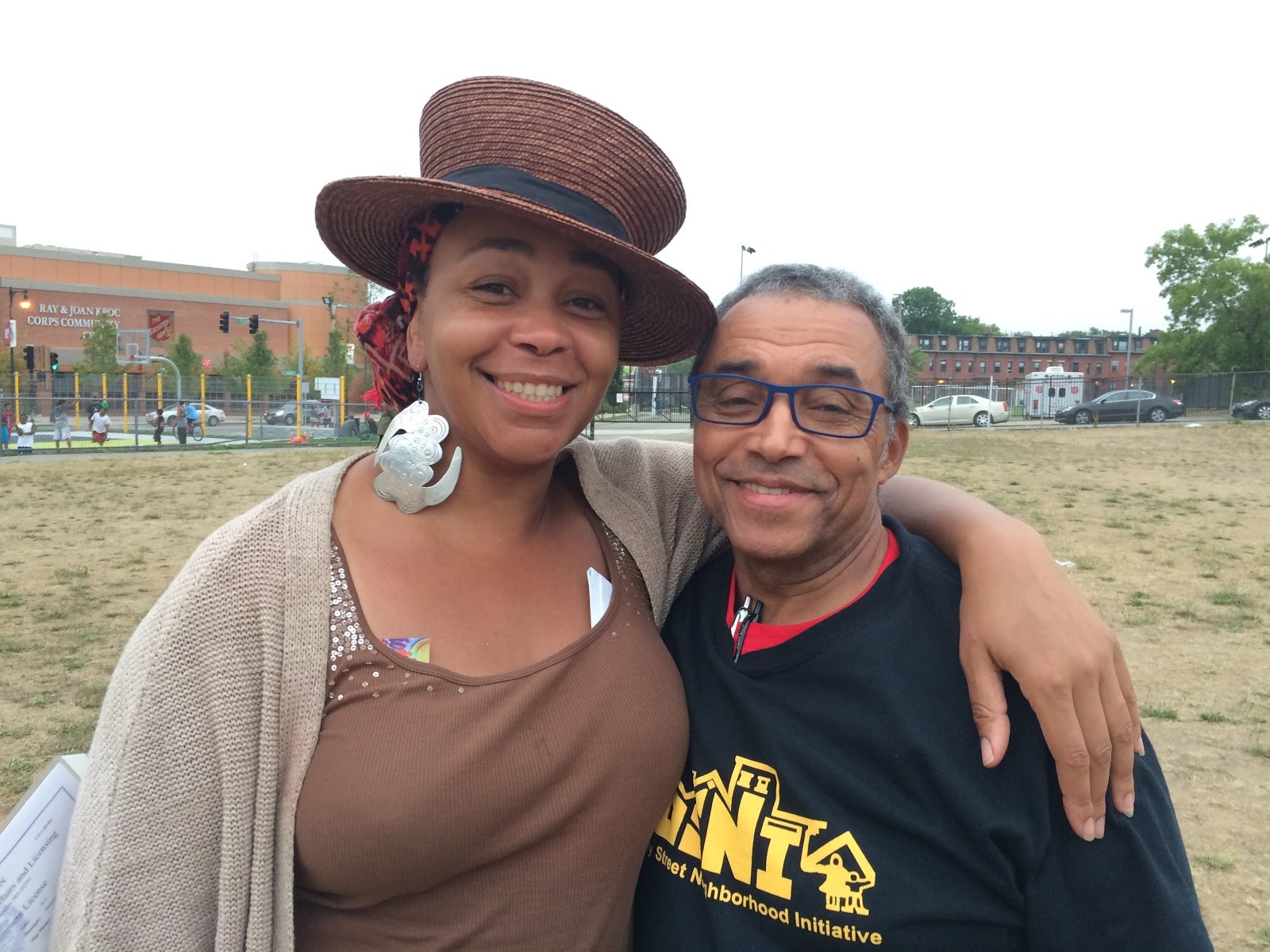 DSNI’s fearless leaders, Ramona Lisa Alexander and Jose Barros, at the 28th Annual Multicultural Festival. Image shows Ramona, in a brown straw top hat, and Jose, in a DSNI T-Shirt and his blue framed glasses, at Mary Hannon Park in Dorchester. Photography by Ros Everdell.